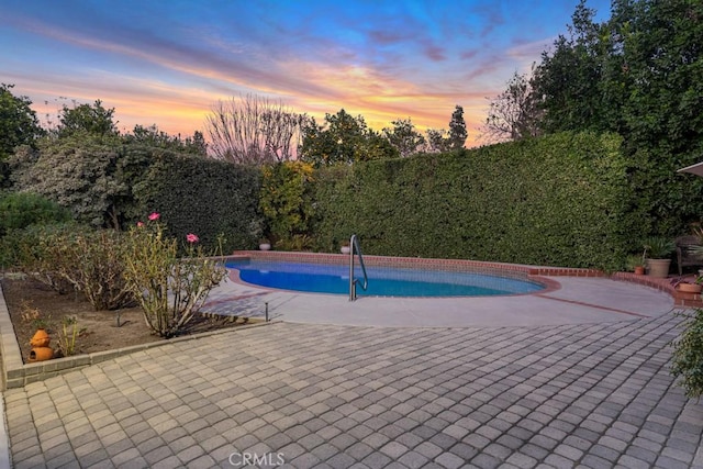 pool at dusk featuring a patio area