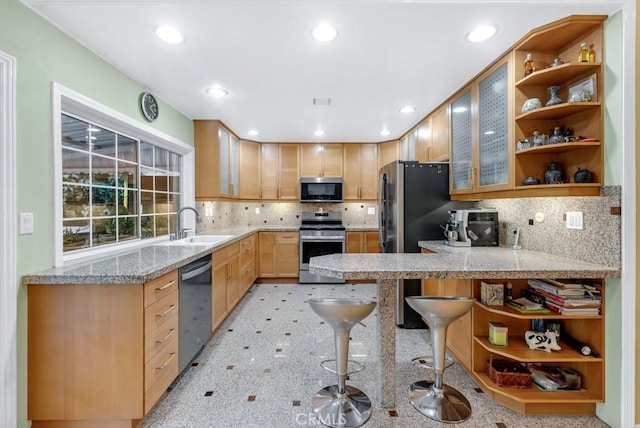 kitchen featuring sink, appliances with stainless steel finishes, a kitchen bar, light brown cabinetry, and kitchen peninsula