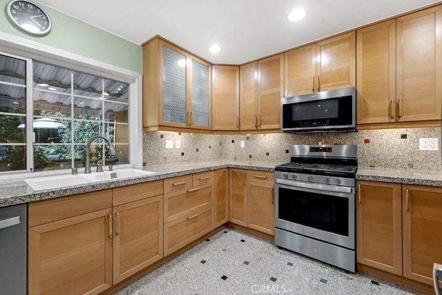 kitchen featuring stainless steel appliances, light stone countertops, sink, and decorative backsplash