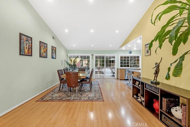 dining space featuring wood-type flooring and high vaulted ceiling