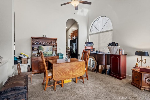 carpeted dining space featuring a towering ceiling and ceiling fan