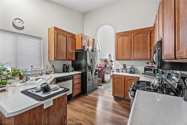 kitchen with sink, light hardwood / wood-style floors, and black appliances