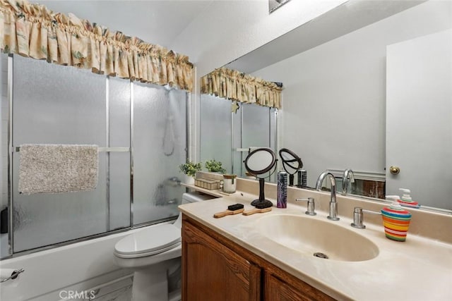 full bathroom featuring vanity, shower / bath combination with glass door, and toilet