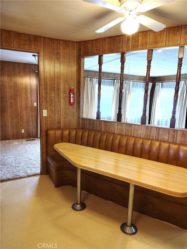 sitting room featuring a ceiling fan, carpet, and wood walls