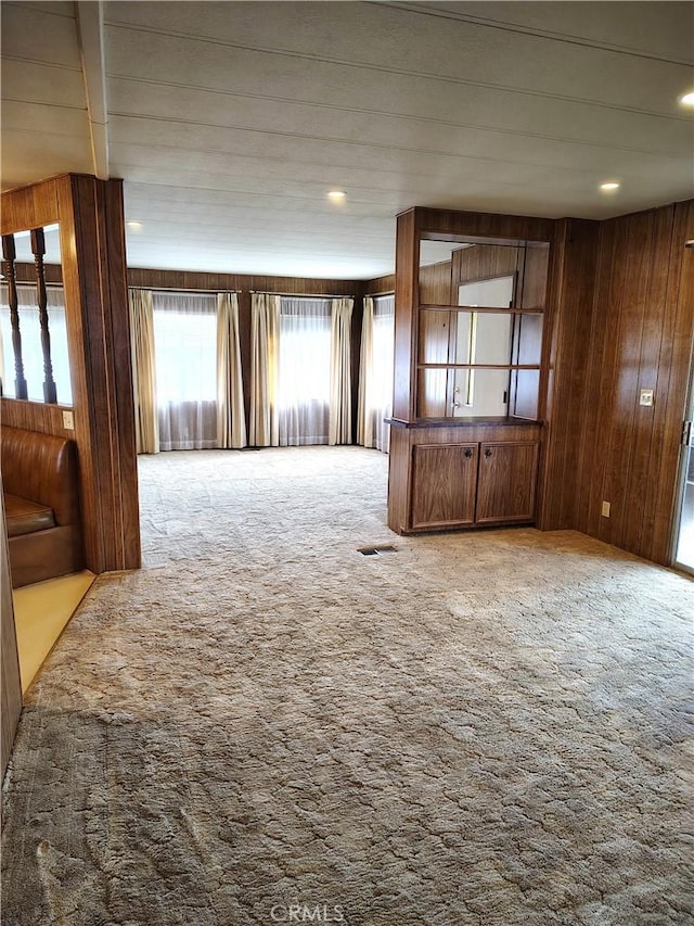 spare room with wood walls, visible vents, and light colored carpet