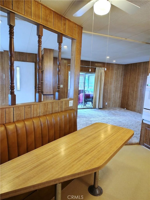 kitchen featuring wood walls, carpet, and a ceiling fan