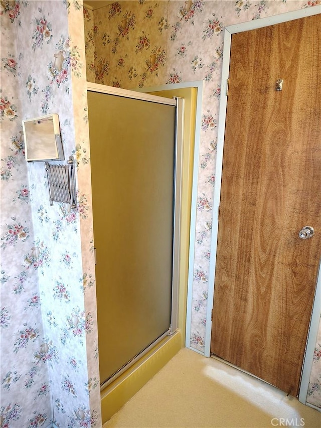 full bath with wallpapered walls and a shower with shower door