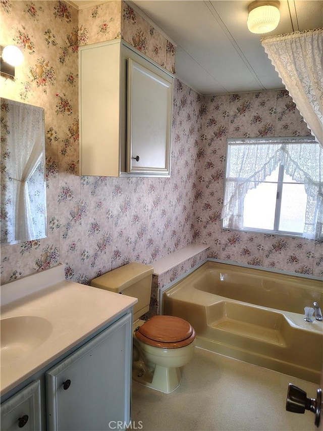 bathroom with toilet, vanity, a bath, and wallpapered walls