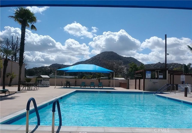 community pool featuring a patio area, a mountain view, and fence