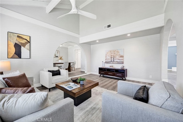 living room featuring high vaulted ceiling, beam ceiling, light hardwood / wood-style floors, and ceiling fan