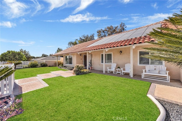 back of property featuring a yard and solar panels