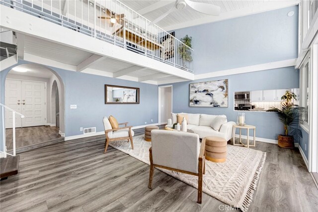 living room with hardwood / wood-style flooring, beamed ceiling, and a high ceiling