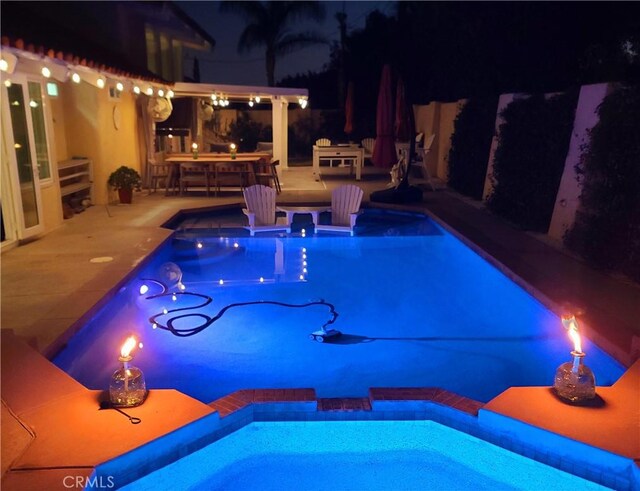 pool at night with a patio area