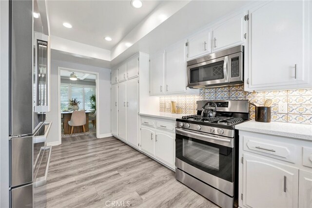 kitchen featuring white cabinetry, tasteful backsplash, stainless steel appliances, and light wood-type flooring