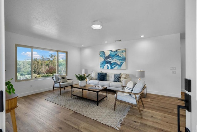 living area with recessed lighting, wood finished floors, visible vents, and baseboards