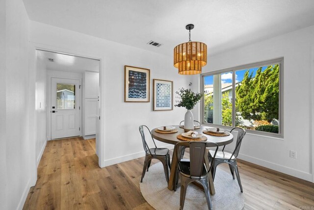 dining space featuring visible vents, light wood-style flooring, and baseboards