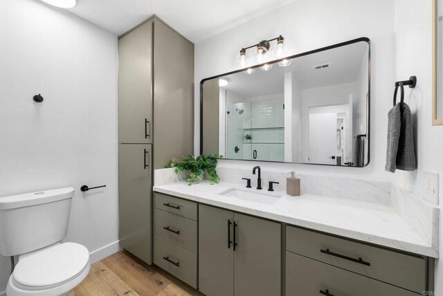 bathroom featuring visible vents, toilet, a stall shower, vanity, and wood finished floors