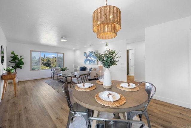 dining room with light wood-style flooring, baseboards, and a notable chandelier