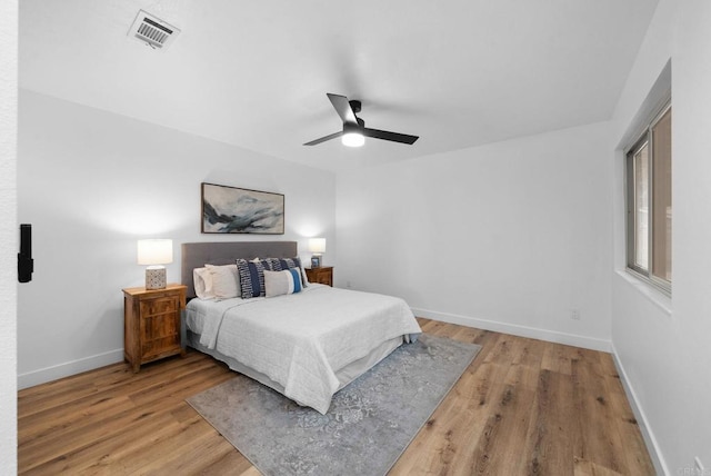 bedroom featuring light wood-style floors, baseboards, visible vents, and ceiling fan