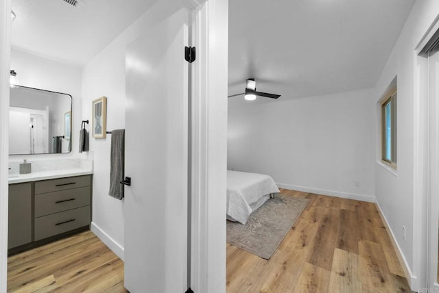 bathroom with a ceiling fan, wood finished floors, vanity, and baseboards