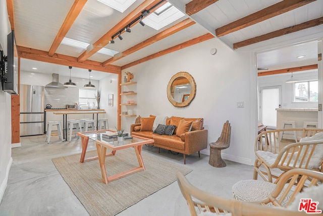 living room featuring beamed ceiling, plenty of natural light, and a skylight