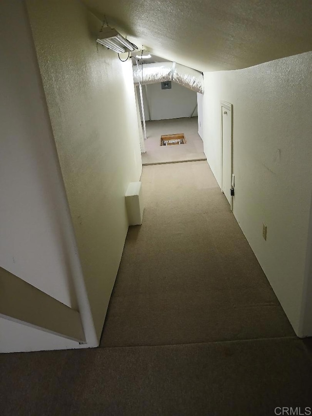 hall with light colored carpet and a textured ceiling