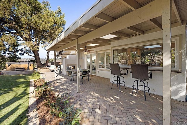 view of patio / terrace with a bar, ceiling fan, and a hot tub