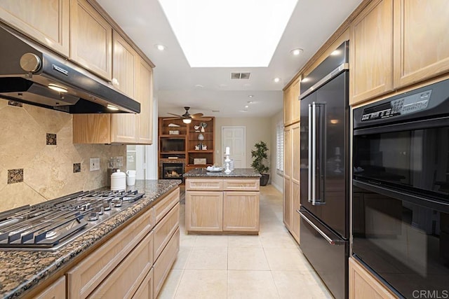 kitchen with black double oven, stainless steel gas stovetop, built in fridge, and dark stone counters