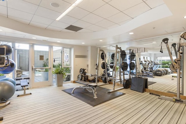 gym with a paneled ceiling and light carpet