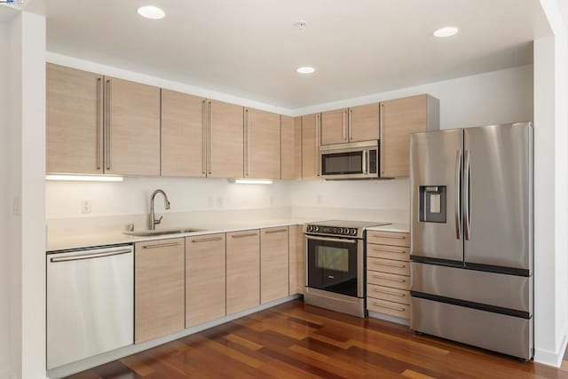 kitchen featuring stainless steel appliances, sink, light brown cabinetry, and dark hardwood / wood-style floors