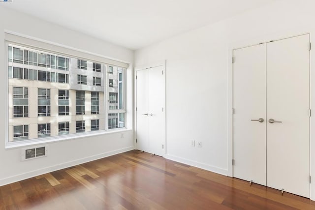 unfurnished bedroom featuring multiple closets and wood-type flooring