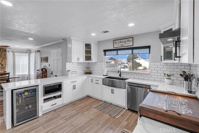 kitchen with wine cooler, sink, stainless steel dishwasher, and white cabinets