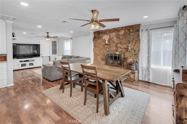 dining area featuring hardwood / wood-style flooring, ornamental molding, ceiling fan, and a fireplace