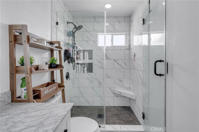 bathroom with vanity, toilet, and a shower with door