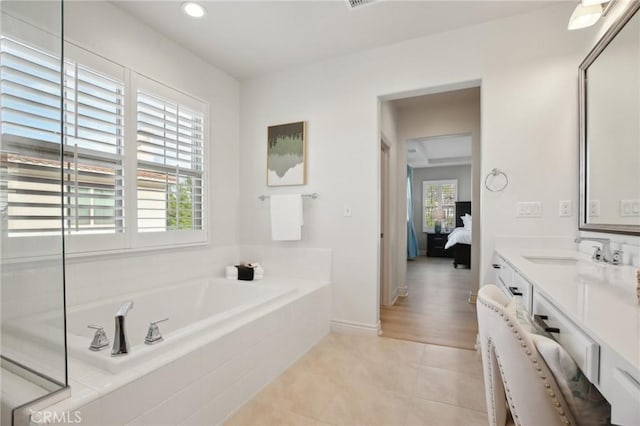 bathroom featuring tile patterned floors, vanity, and tiled tub