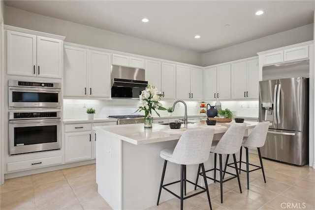 kitchen featuring stainless steel appliances, an island with sink, and white cabinets