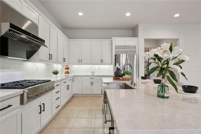 kitchen with stainless steel appliances, tasteful backsplash, ventilation hood, white cabinets, and light tile patterned flooring