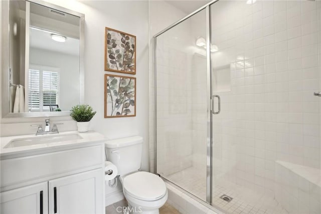 bathroom featuring vanity, toilet, and a shower with door