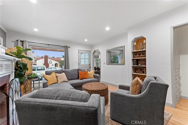 living room featuring crown molding, a fireplace, and light hardwood / wood-style flooring