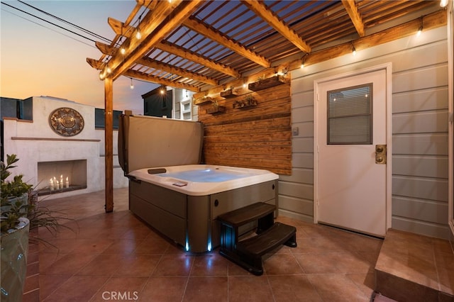 patio terrace at dusk featuring a pergola and a premium fireplace