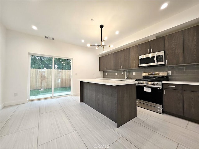 kitchen with decorative light fixtures, sink, a center island, dark brown cabinetry, and stainless steel appliances