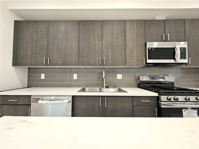 kitchen with appliances with stainless steel finishes, sink, backsplash, and dark brown cabinetry