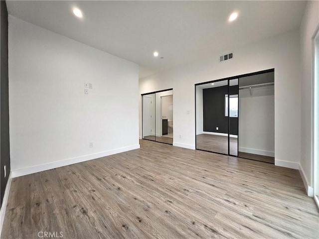 unfurnished bedroom with multiple closets and light wood-type flooring