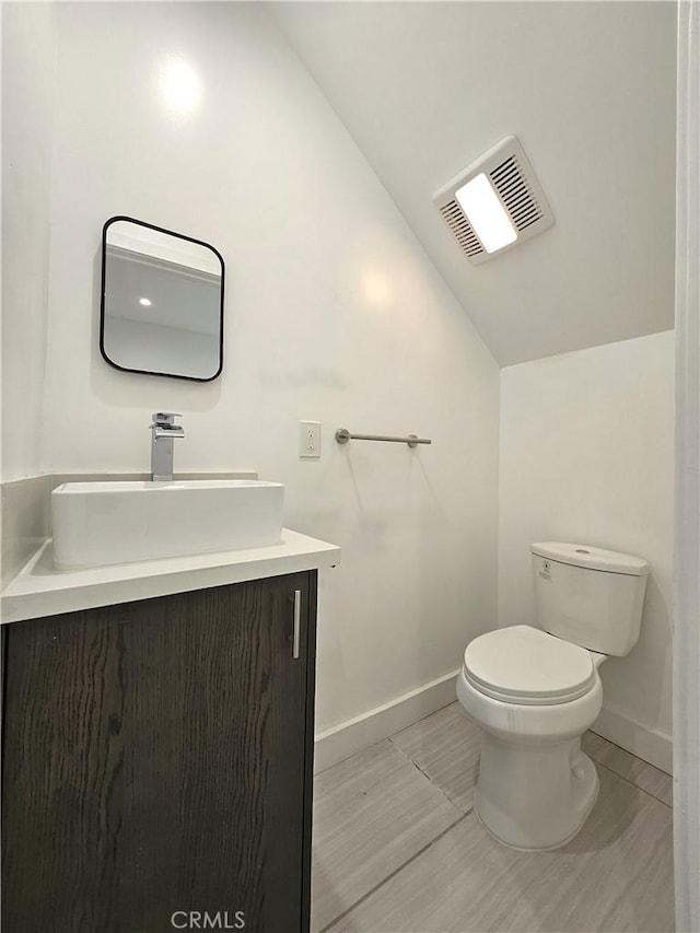 bathroom with vanity, toilet, and vaulted ceiling