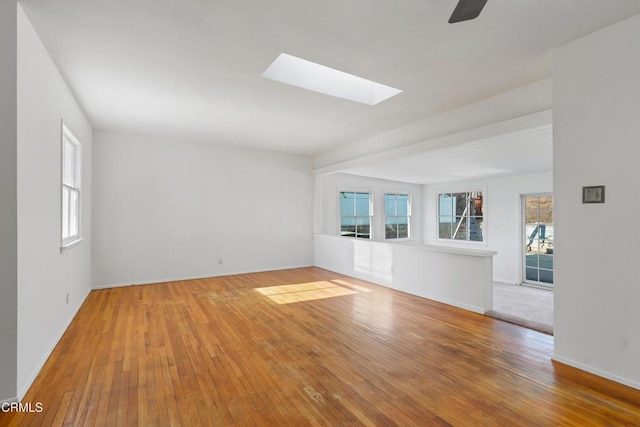 unfurnished room with hardwood / wood-style floors, ceiling fan, and a skylight