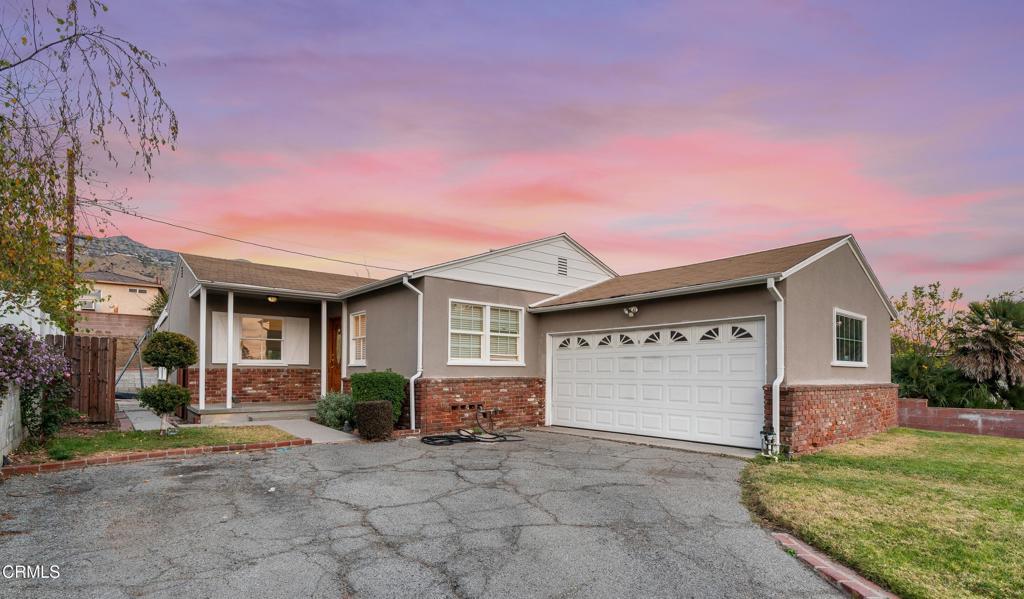 ranch-style home featuring a garage and a lawn