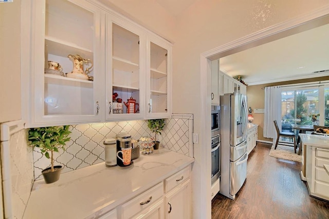 kitchen with appliances with stainless steel finishes, backsplash, dark hardwood / wood-style floors, light stone counters, and white cabinets