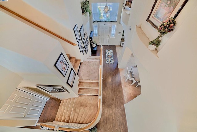 stairway with hardwood / wood-style flooring and a high ceiling