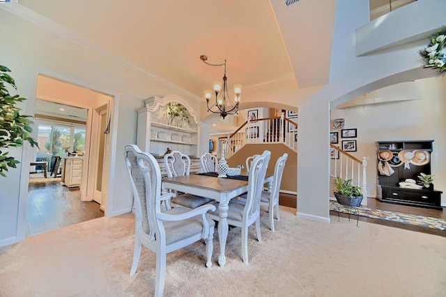 carpeted dining area with crown molding and an inviting chandelier