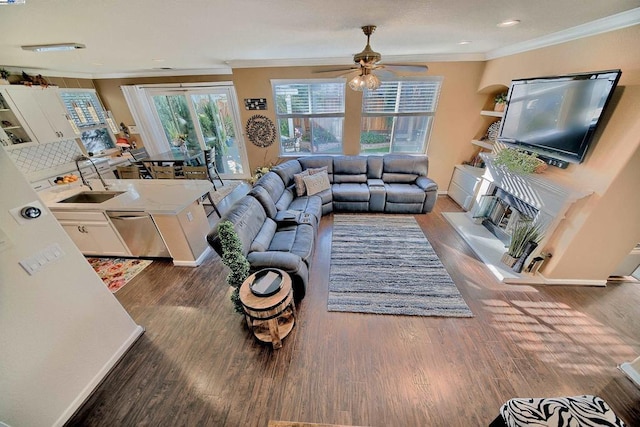 living room with ornamental molding, dark wood-type flooring, and ceiling fan